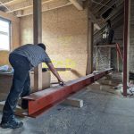 Handwerker richtet einen Stahlträger im Innenraum während der Sanierung aus