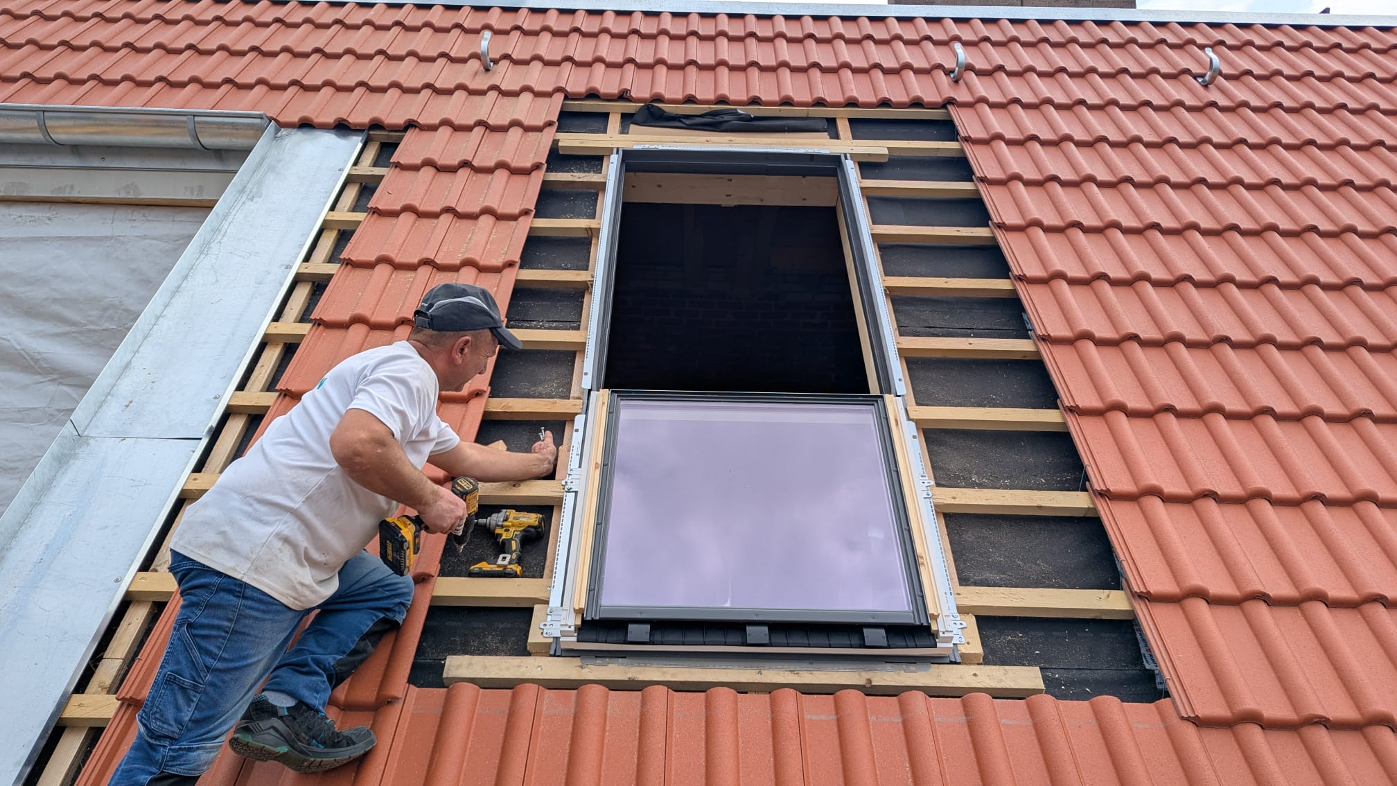 Handwerker beim fachgerechten Einbau eines Dachfensters in ein Ziegeldach in Brandenburg an der Havel